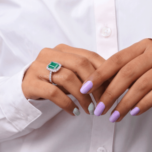 green emerald cut lab gemstone halo engagement ring on model's finger