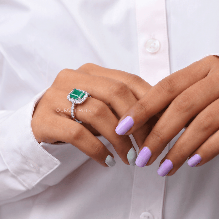 green emerald cut lab gemstone halo engagement ring on model's finger