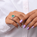 green emerald cut lab gemstone halo engagement ring on model's finger