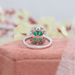 green emerald cut gemstone halo engagement ring's back view on jewelry box