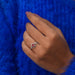 In finger front view of cushion cut solitaire engagement ring in 14k white gold.