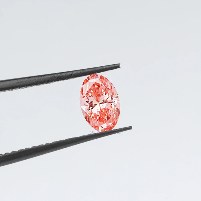 0.6 carat pink lab grown oval diamond loose held with tweezer