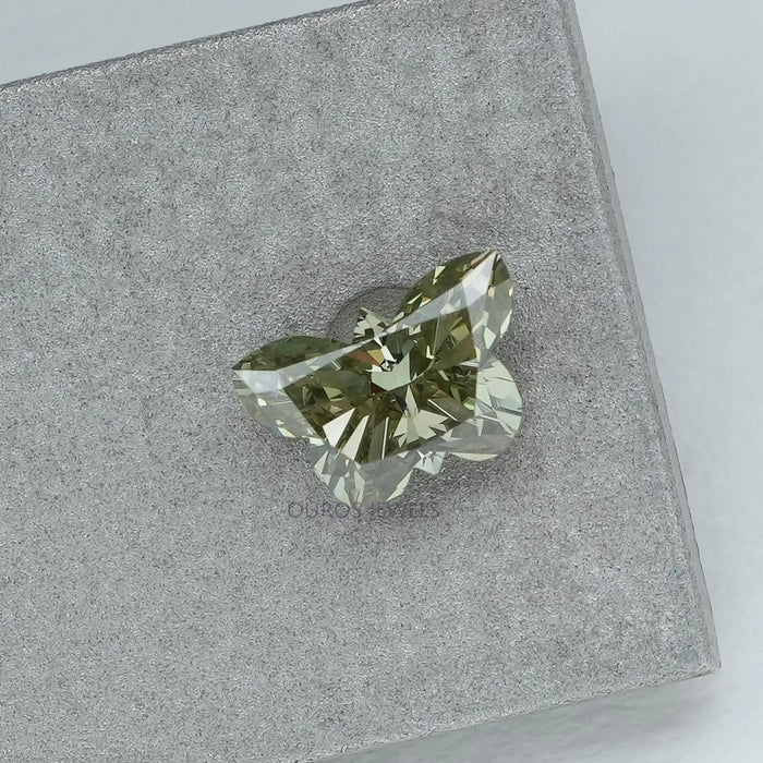 side view of green butterfly shaped lab diamond on matte material