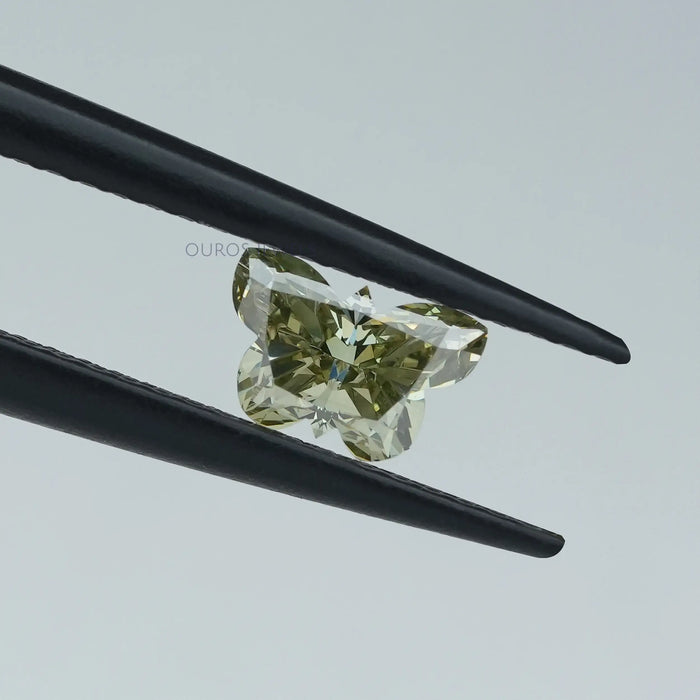 green butterfly cut lab created diamond held with tweezer