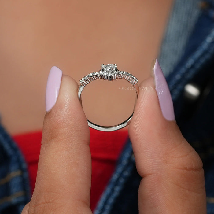 Two finger front view of heart cut diamond ring, main center stone colorless with VS clarity.