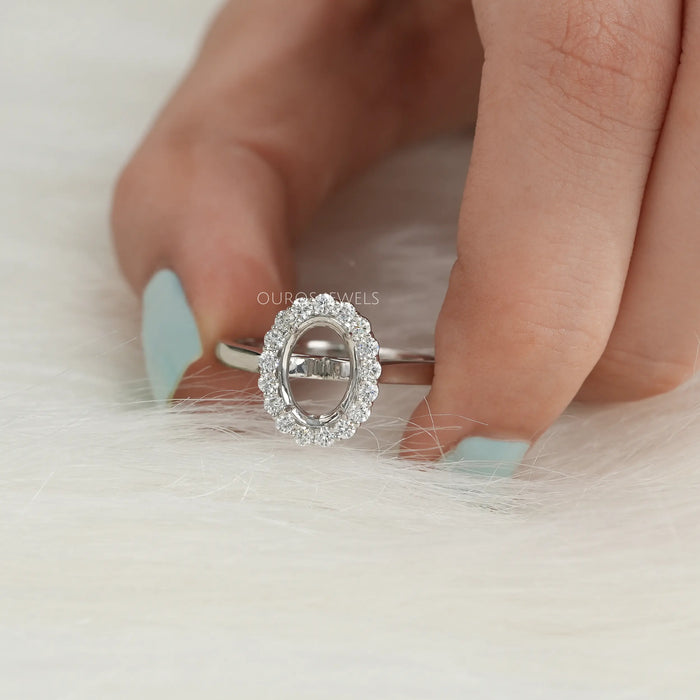 close view of oval-shaped halo semi-mount engagement ring on grey fabric