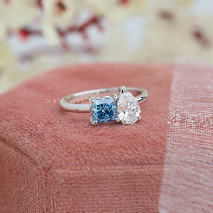 side view of blue princess-cut and pear diamond toi et moi wedding ring on jewelry box