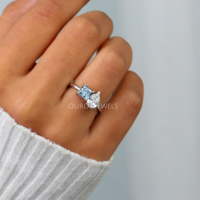 blue princess-cut and pear diamond toi et moi engagement ring on model's finger