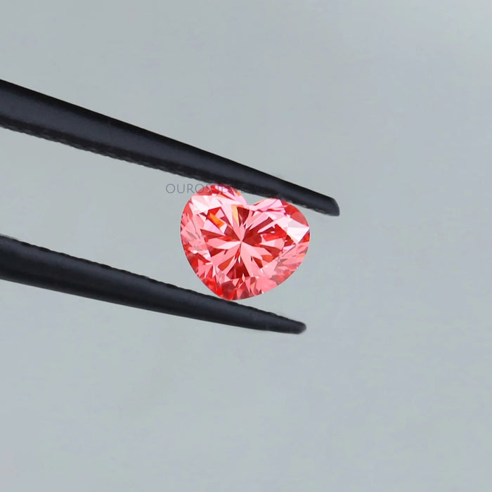 pink heart shaped lab created diamond held with tweezer