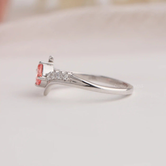 Side view of oval cut diamond engagement ring with curved band & pink color oval diamond.