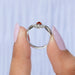 Two finger view of red oval diamond infinity ring with crafted  side round small diamonds.