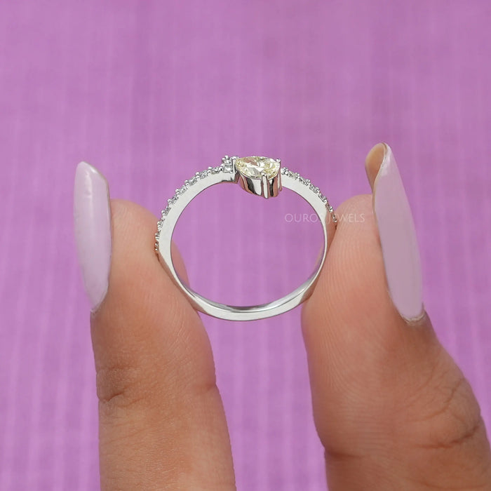 A close up look of shining pear shaped solitaire diamond engagement ring with a stylish curved shank